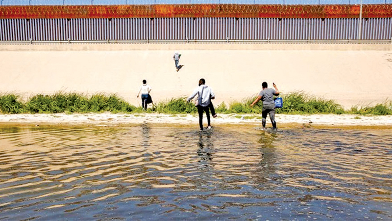 Asylum-seeking migrants walk out of the Rio Bravo river after crossing it to turn themselves in to US Border Patrol agents to request asylum in El Paso, Texas, US, as seen from Ciudad Juarez, Mexico on April 13, 2022.