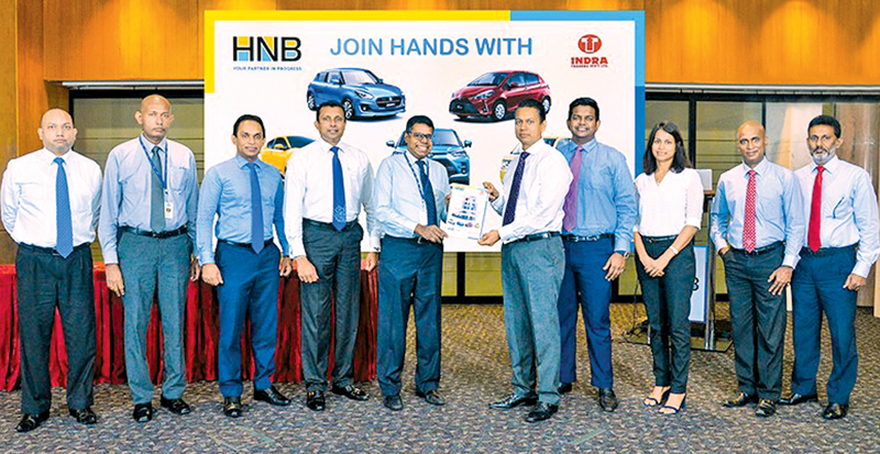 HNB Chief Operating Officer, Dilshan Rodrigo exchanging the MoU with Indra Traders MD Rushanka Silva. Also pictured are Mahesh Ratnayake, Roshan De Silva, Niluka Amarasinghe, Kanchana Karunagama, Hashindra Silva, Sajini Silva, Rasika De Silva, and Laxman Weerasinghe.