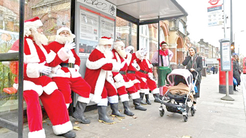 Santas wait at a bus stop as they take a break from the classroom during Santa School at The Ministry of Fun in London on Saturday.