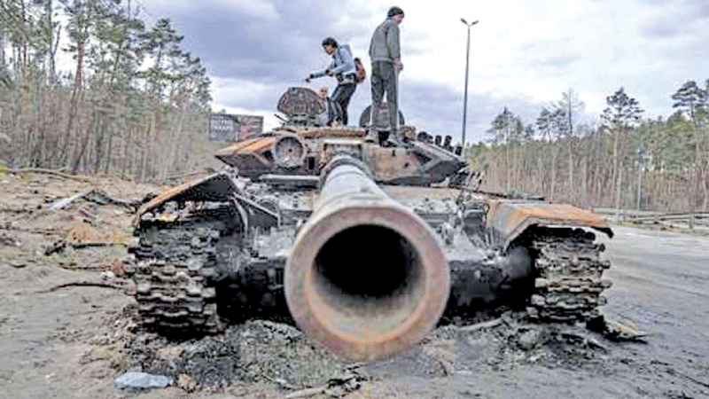 Ukrainian youths climb to inspect a tank destroyed during fighting between Russian and Ukrainian forces in Mariupol. 