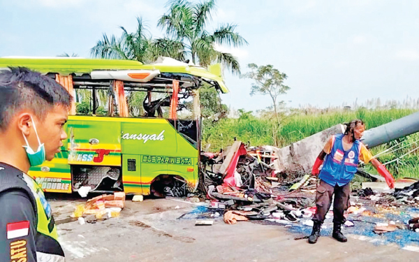 Rescuers inspect the wreckage of a tourist bus that crashed into a street sign on a highway in Mojokerto, East Java, Indonesia on Monday.