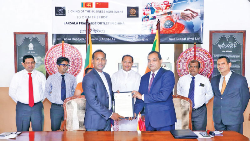 Sala Group Chairman/MD Chinthaka Wijewickrama,  signing the partnership agreement with Lakmal Wickramaarachchi while Minister Dayasiri Jayasekara looks on.