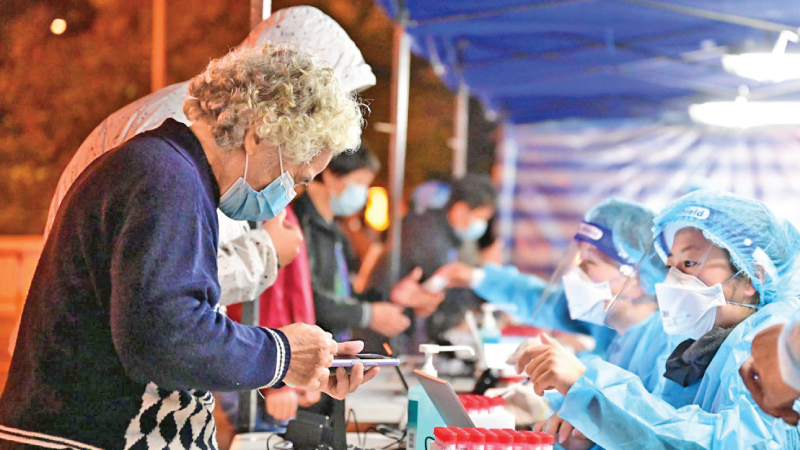 A medical worker registers personal information of a woman at a COVID-19 testing site in Hong Kong.