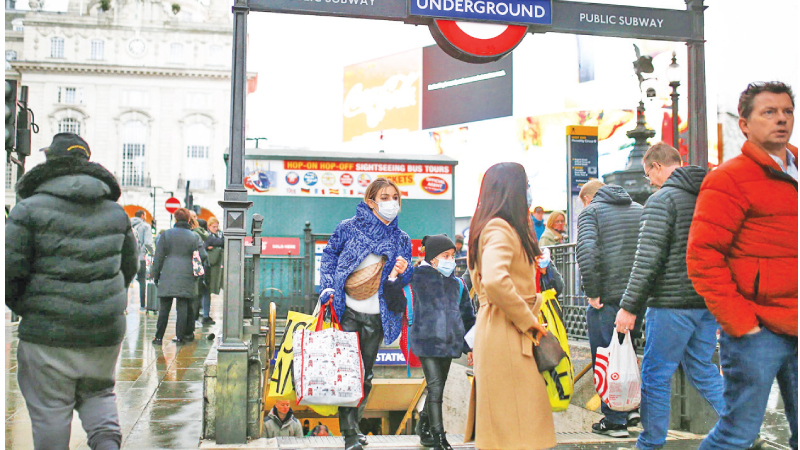 People wearing protective face masks leave Piccadilly Circus underground station in central London, Britain.