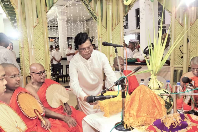 Minister Dr. Bandula Gunawardhana, giving alms to monks participating the all-night pirith chanting ceremony.